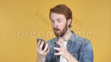 红发人在使用智能手机时为成功而兴奋，黄色背景